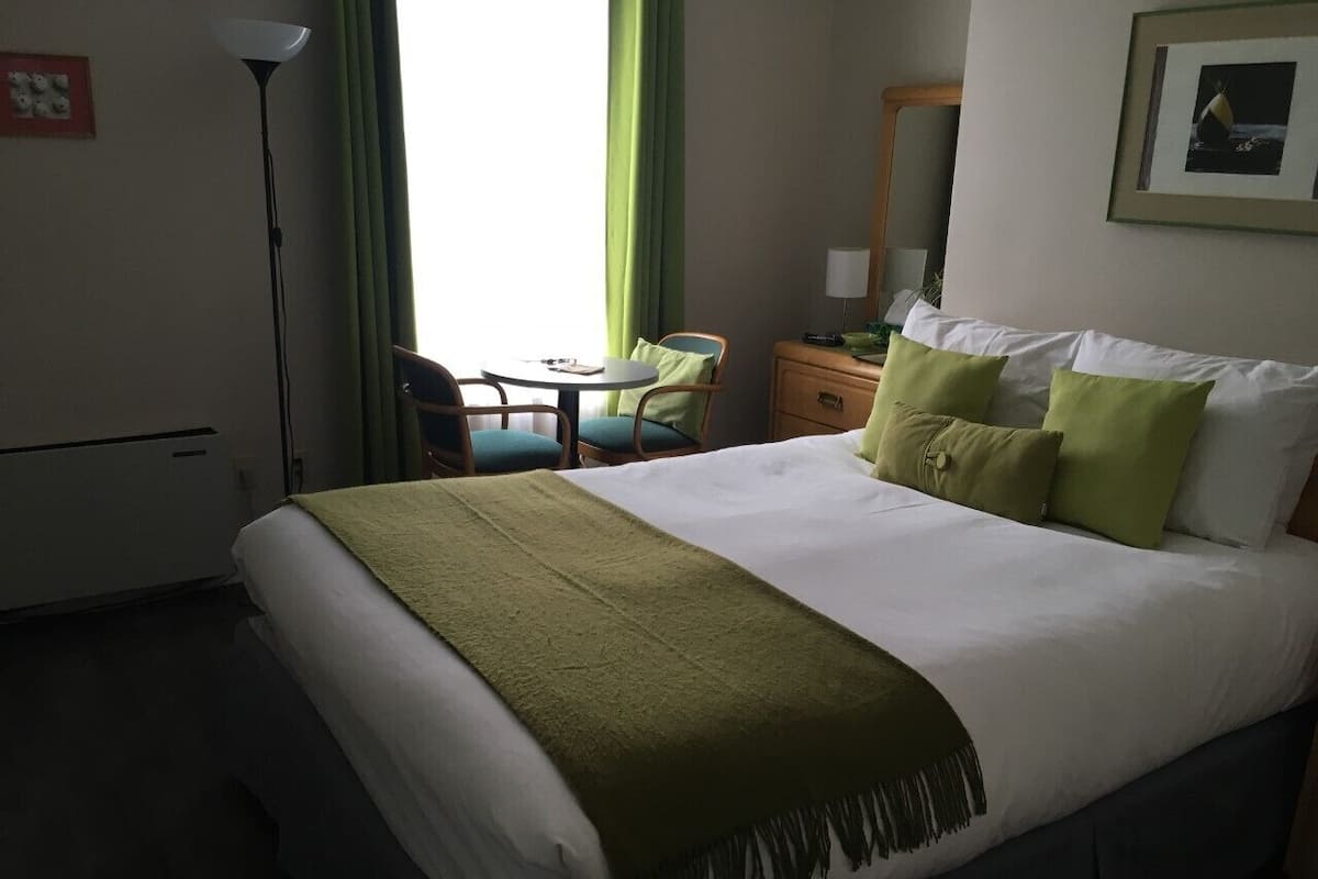 Una habitación de hotel con una cama, un escritorio y una silla.