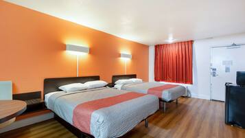 Habitación de hotel con dos camas, un escritorio y una silla. Cuenta con dos luces instaladas en la pared y una puerta con cerradura.