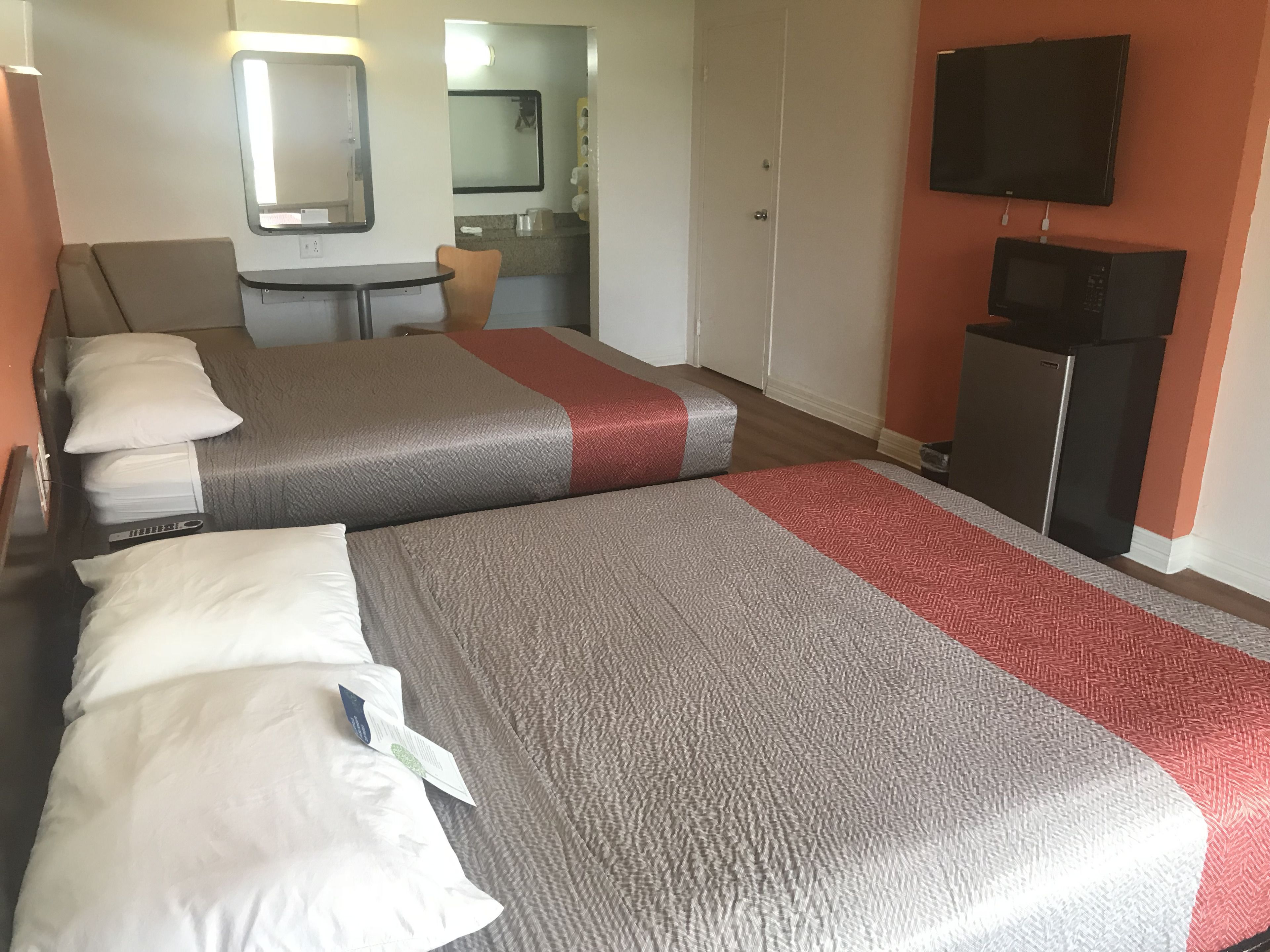 Une chambre d’hôtel avec deux lits, une télévision, un four à micro-ondes et une petite kitchenette.