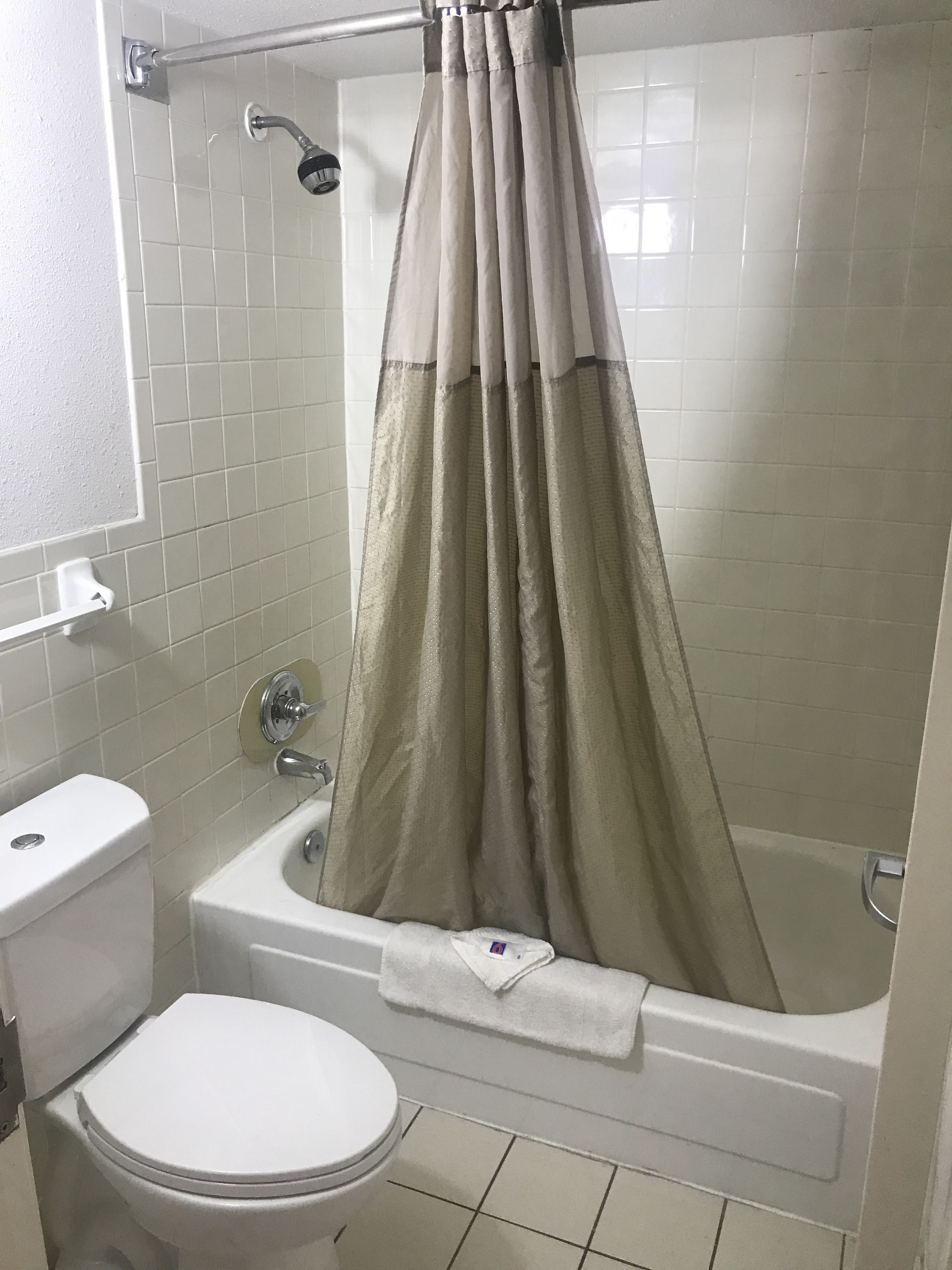 A bathroom with a bathtub, toilet, and shower curtain.