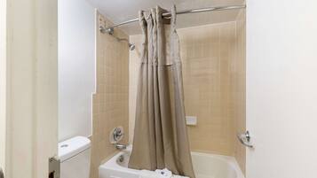 A bathroom with a bathtub, a toilet, and a shower curtain.