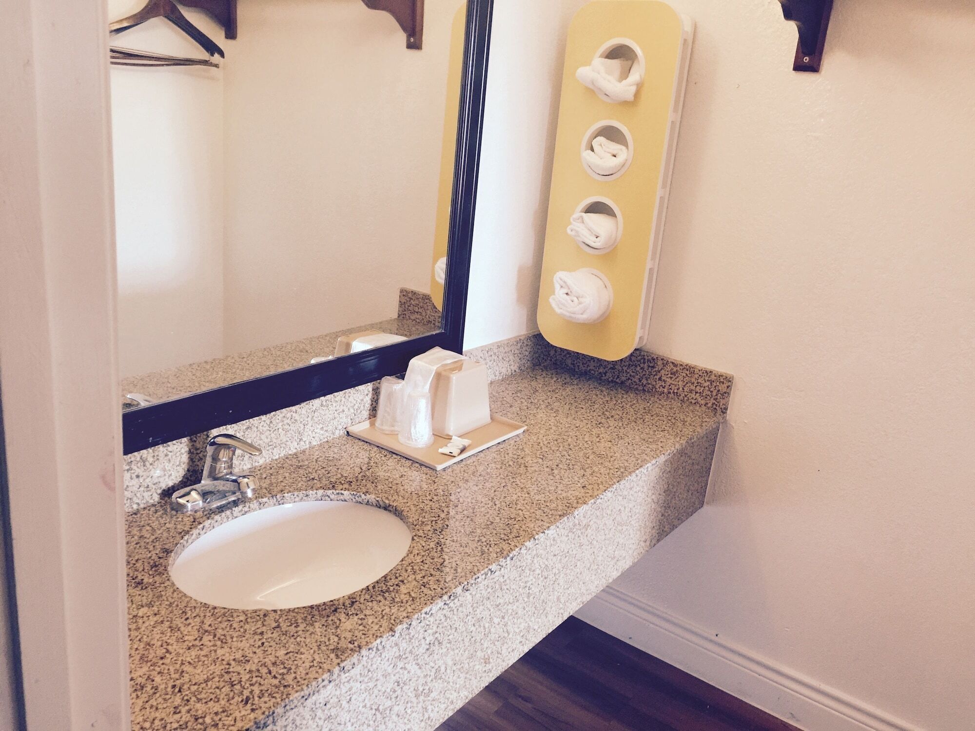 A bathroom with a granite countertop, a white sink, a mirror, and a towel dispenser.