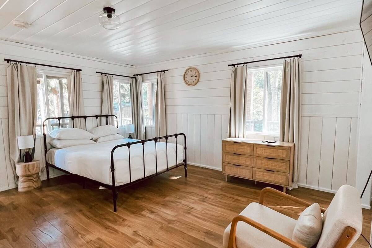 A bedroom with a bed, dresser, chair, and a clock on the wall.