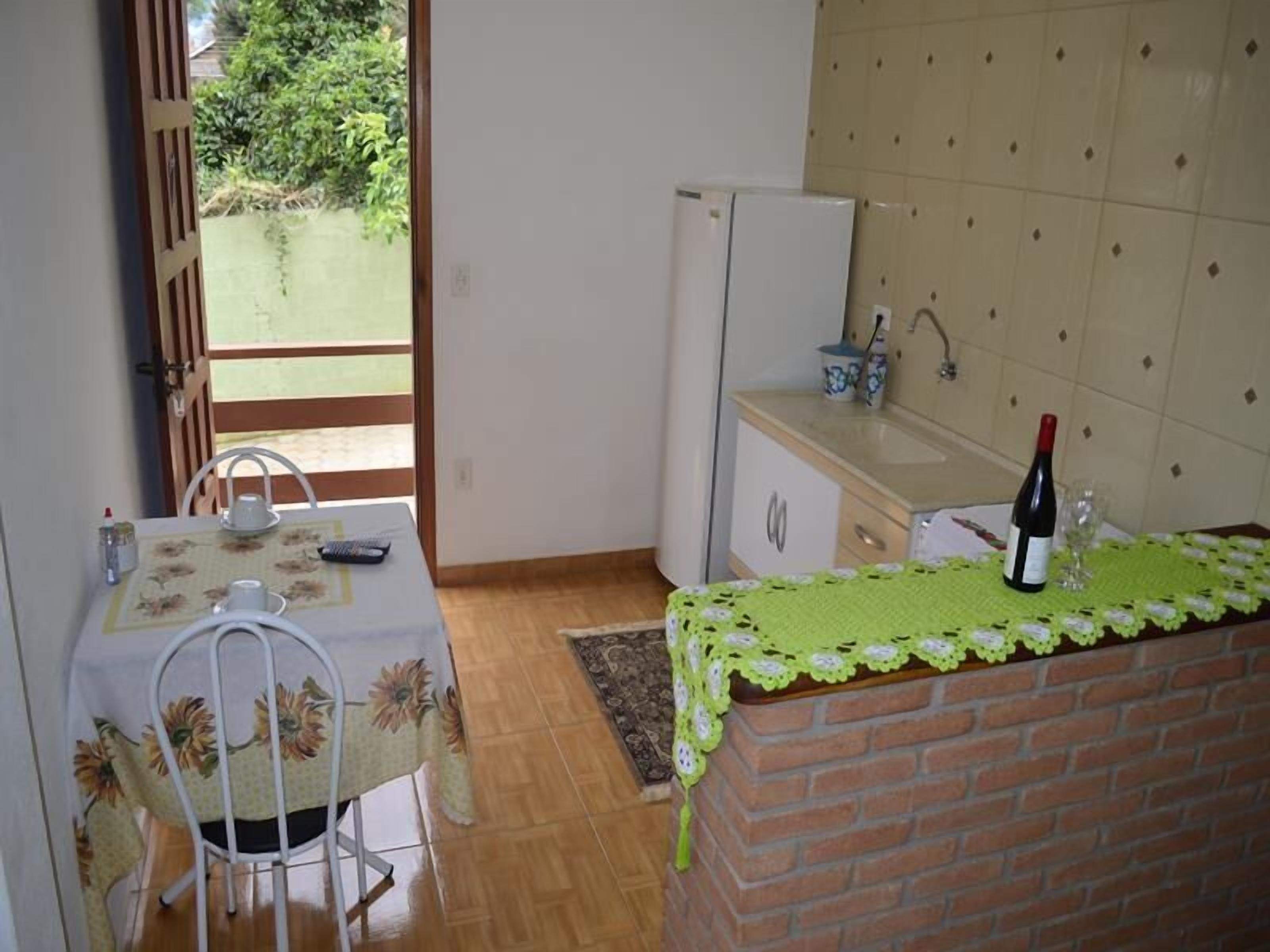 Uma cozinha compacta com geladeira, pia e mesa com cadeiras.