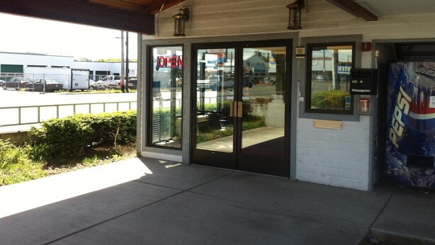A building entrance with a 'OPEN' sign, a wooden ceiling, and a Pepsi vending machine. - Crown Inn (Seattle)