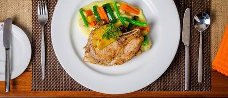 A plate of food with a piece of meat, vegetables, and sauce.