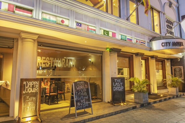 A hotel entrance with flags, a restaurant sign, and a sign for the 2019 World Cup. - Kandy City Hotel by Earl's (Kandy)