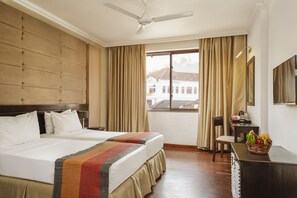 Een hotelkamer met een groot bed, een bureau met een fruitmand, een stoel en een televisie aan de muur.