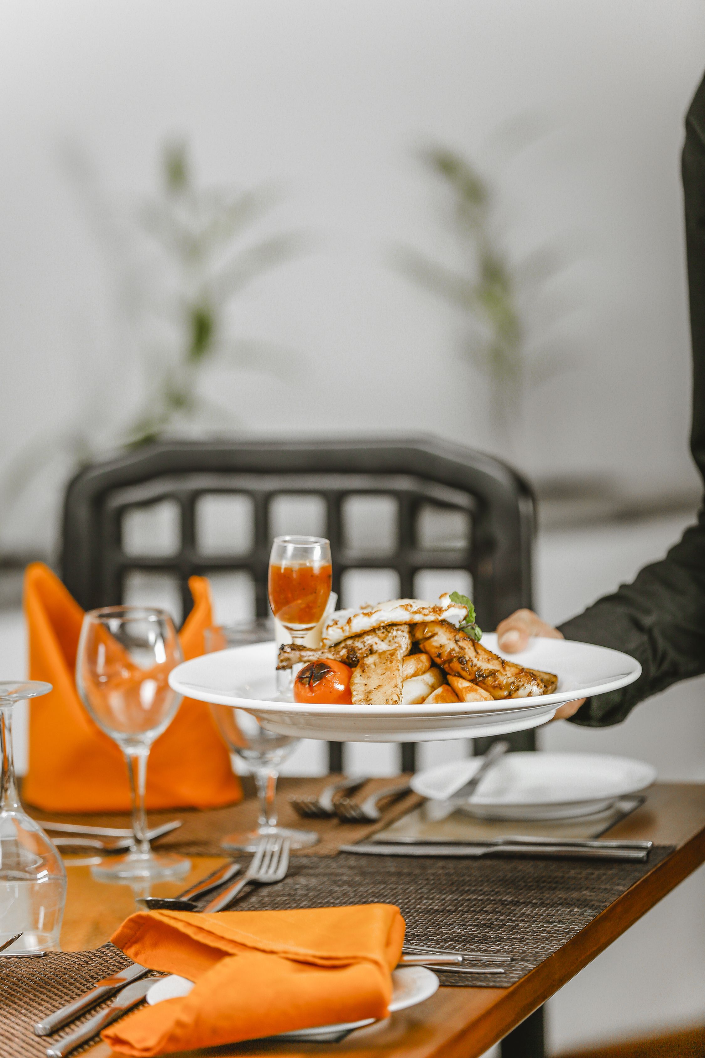 A dining table set with a plate of food, cutlery, and a glass of beverage.