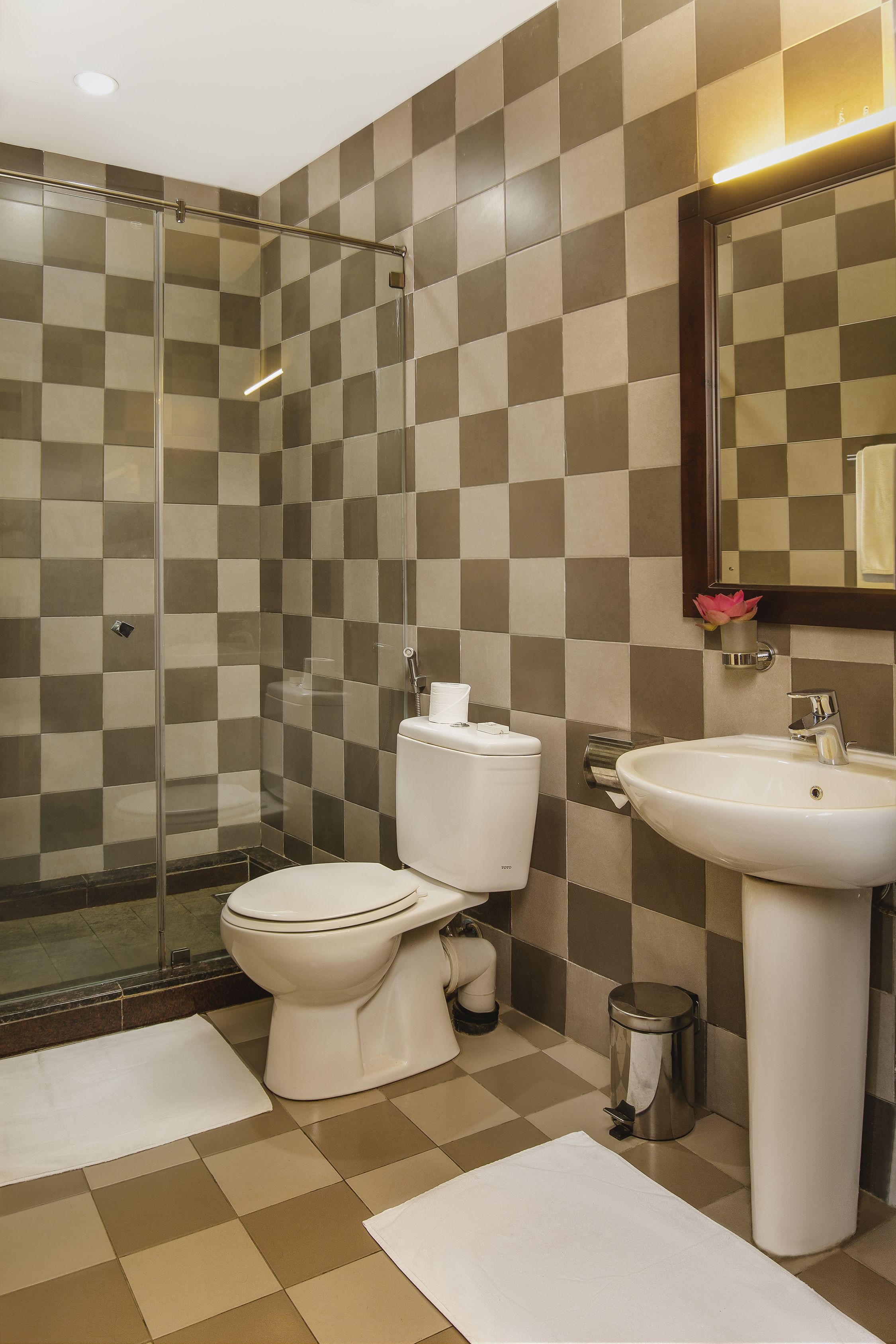 Ein Badezimmer mit Duschkabine, Toilette, Waschbecken und Mülleimer.