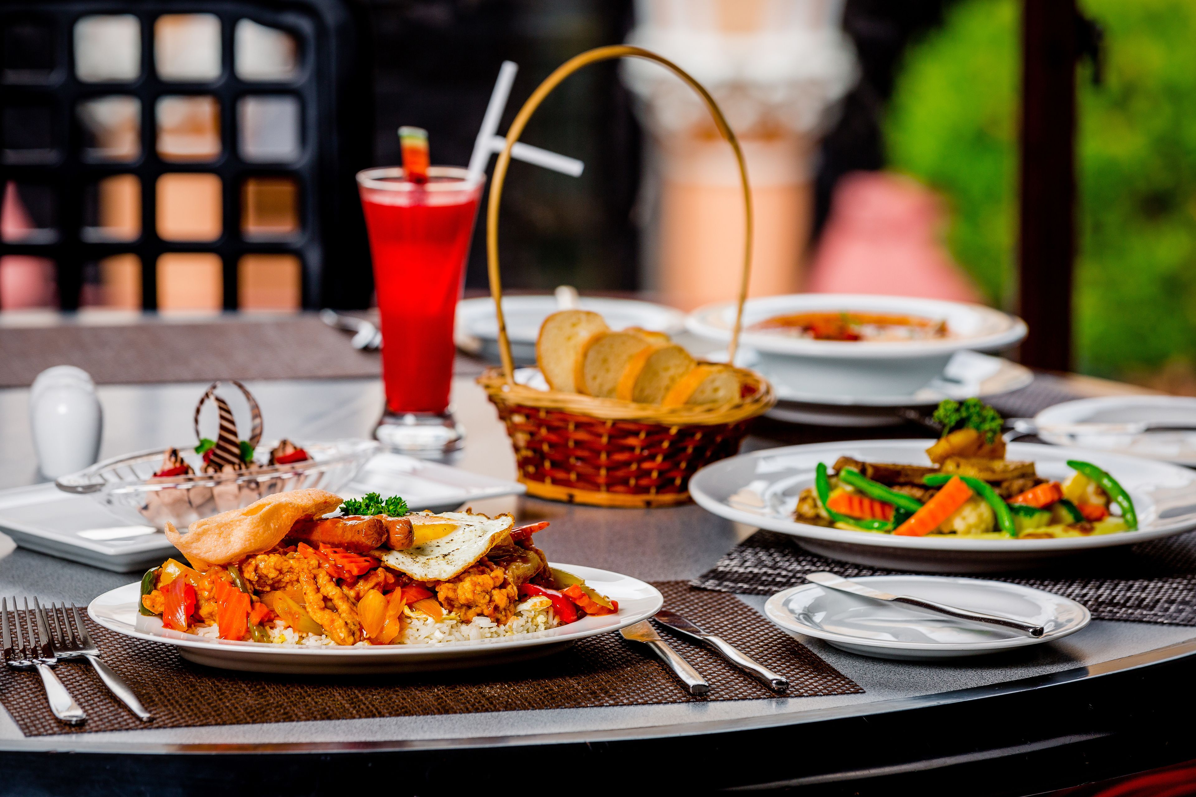 Una mesa dispuesta con diversos platos, entre ellos arroz, verduras y pan, con una bebida al fondo.