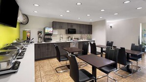 A modern kitchen with a microwave, coffee machine, and a buffet area with multiple serving stations. - Super 8 Fort McMurray (Fort McMurray)