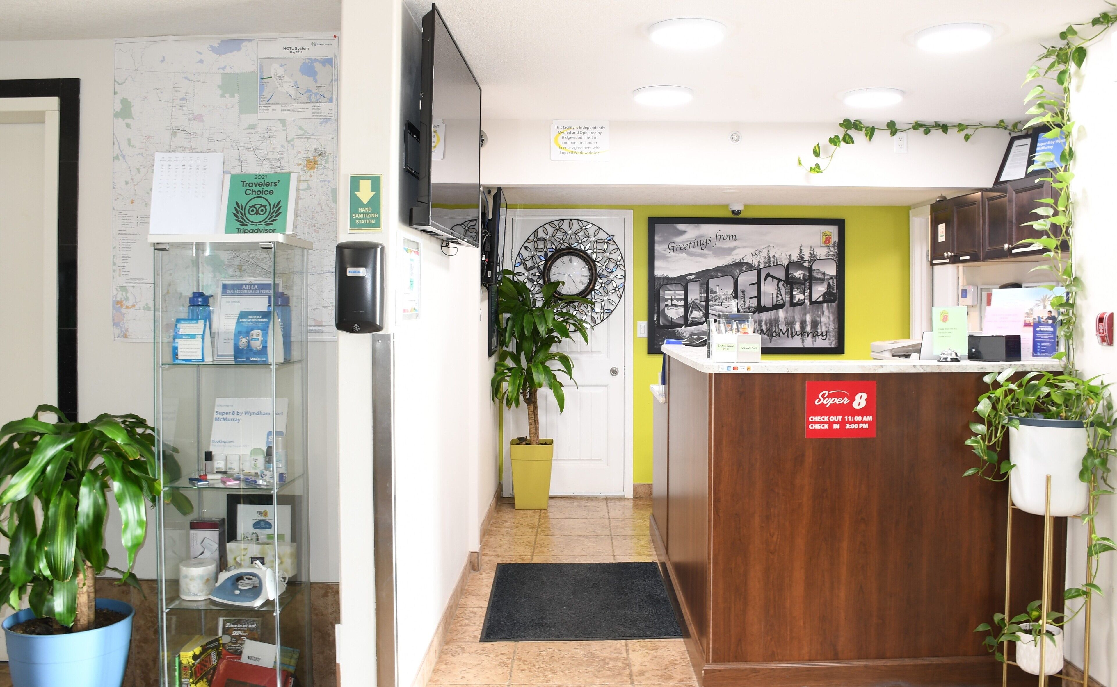Un área de recepción con un mostrador de madera, un dispensador de gel antibacterial, un mapa en la pared y un reloj.
