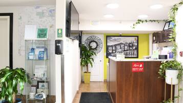 Un área de recepción con un mostrador de madera, un dispensador de gel antibacterial, un mapa en la pared y un reloj.