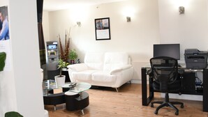 A modern office with a white leather chair, a glass table, a black office chair, and a printer. - Super 8 Fort McMurray (Fort McMurray)