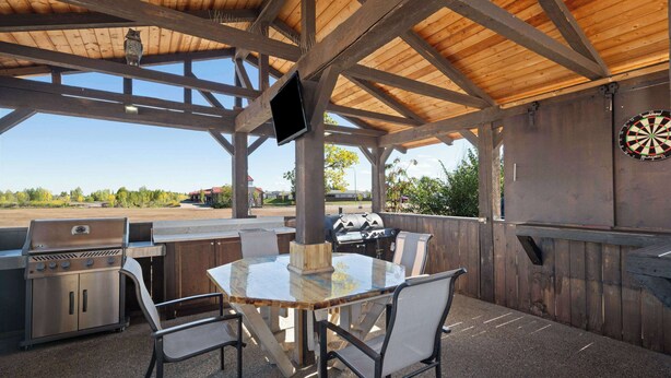 An outdoor patio with a wooden ceiling, a table with chairs, a grill, and a dartboard. - Super 8 Fort McMurray (Fort McMurray)