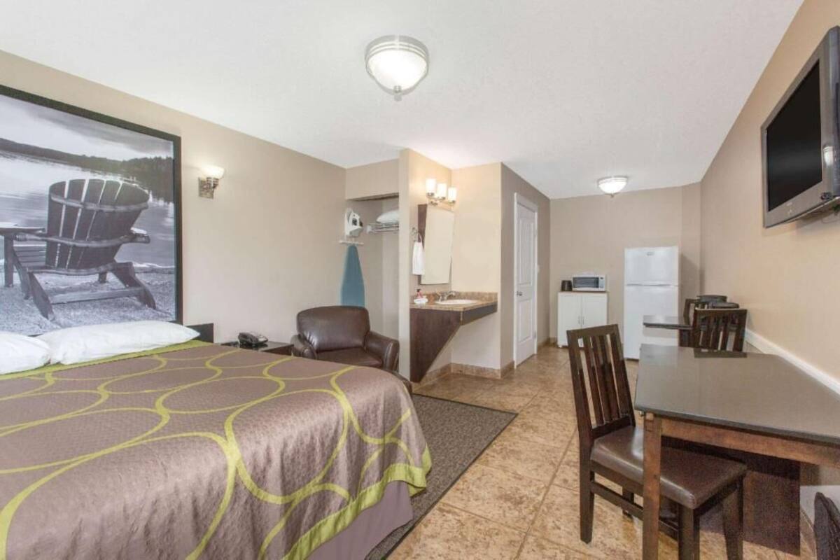 A hotel room with a bed, a desk, a chair, a television, a bathroom, and a view of a lake.