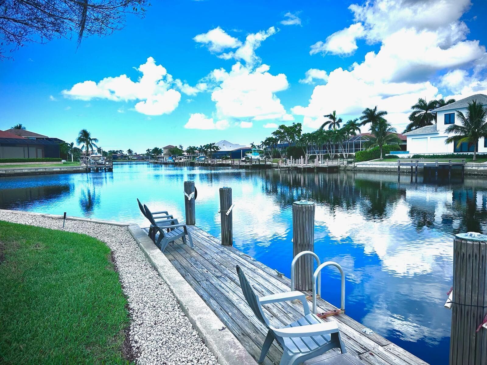 A waterfront property with a dock, chairs, and a clear view of the water.
