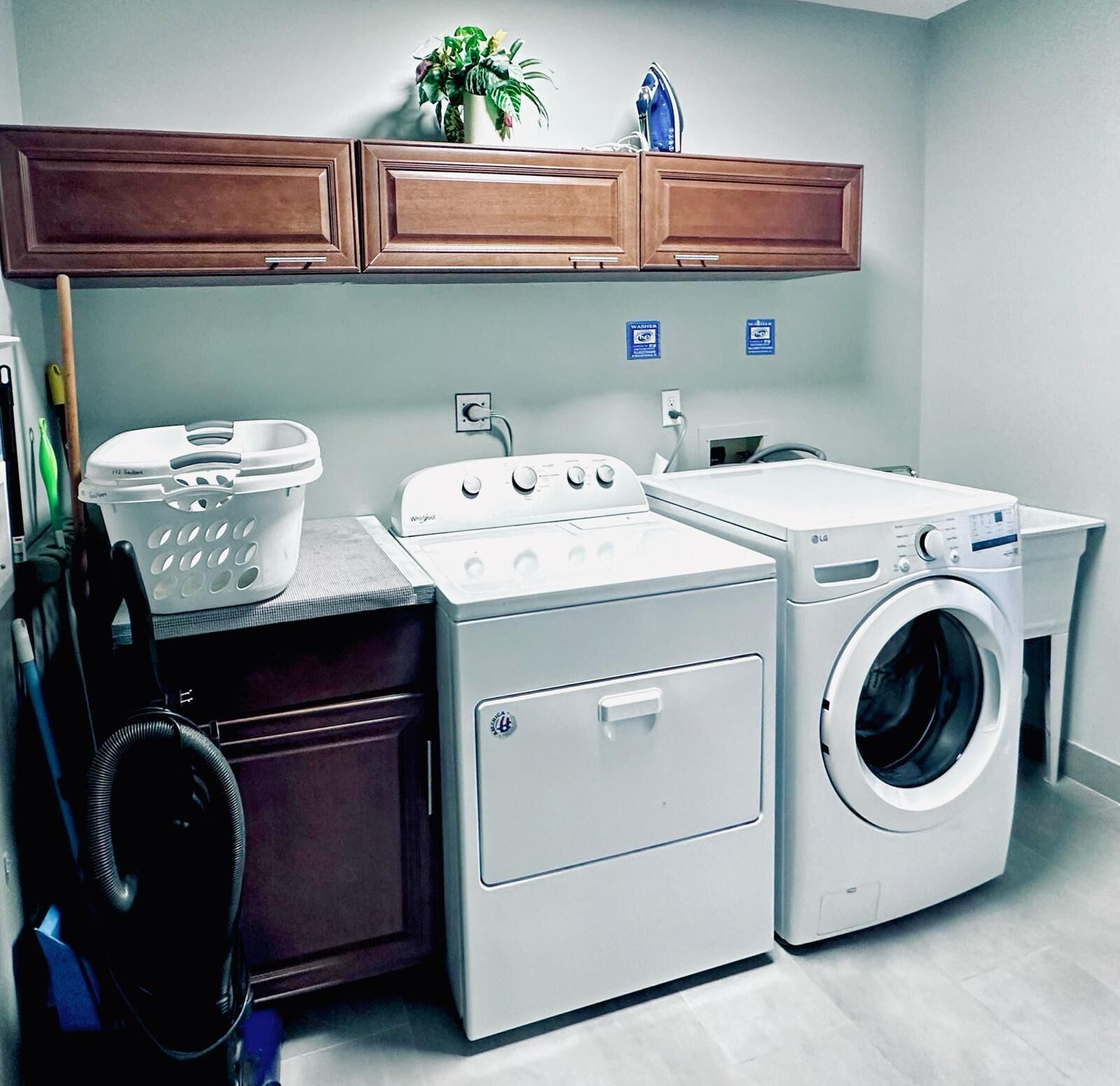 A compact laundry area with a washing machine, dryer, and a wooden cabinet above.