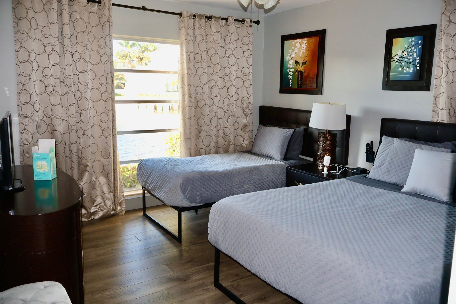 Une chambre d’hôtel avec deux lits, un bureau, une table de chevet et une fenêtre avec des rideaux.