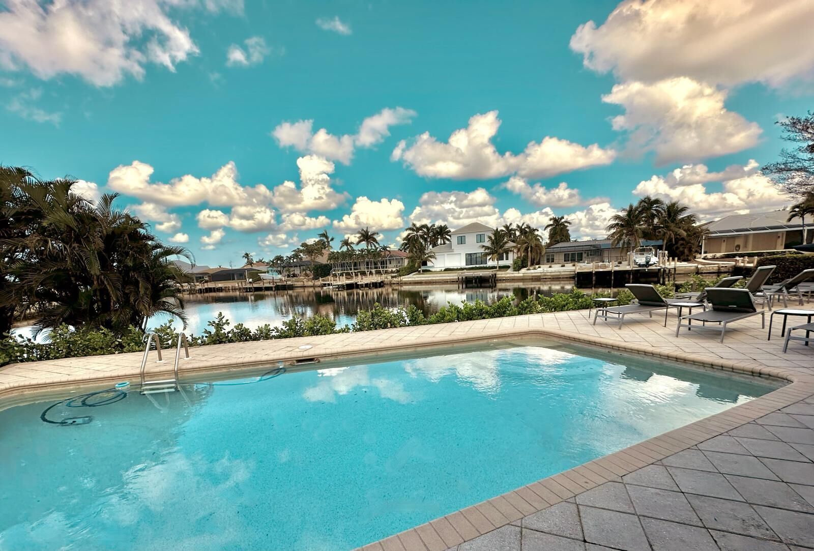 Una piscina con vistas despejadas del entorno, que incluye un cuerpo de agua y palmeras.