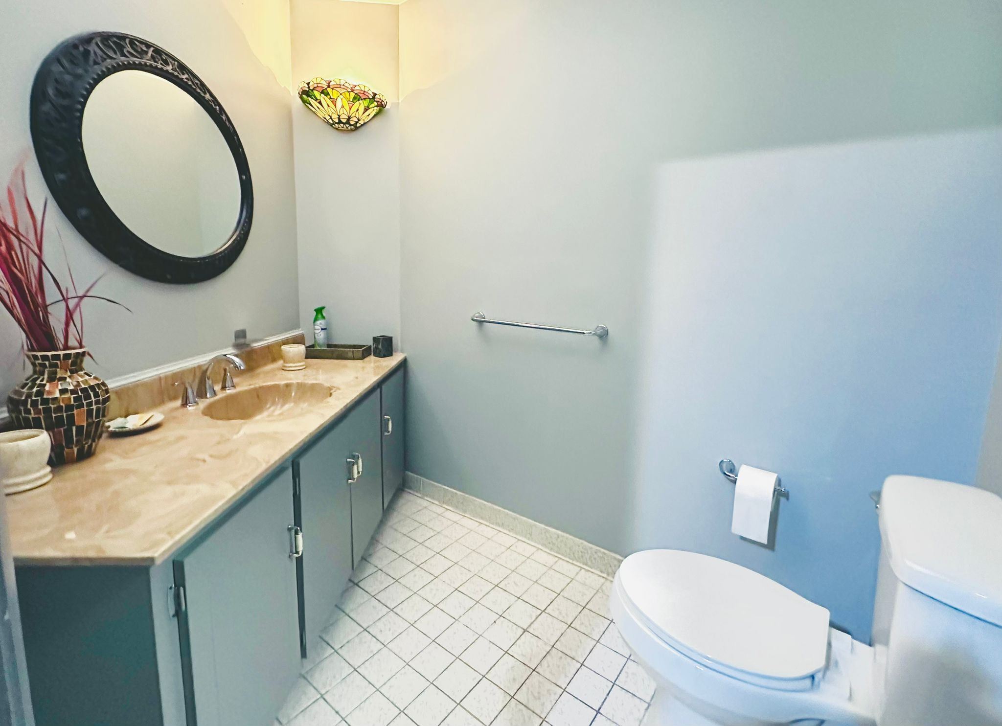 A bathroom with a sink, mirror, toilet, and a towel rack.
