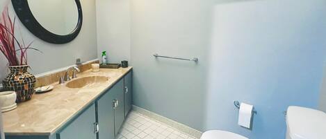 Un baño con lavabo, espejo, inodoro y toallero.