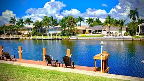 A waterfront hotel with a pool, outdoor seating, and palm trees. - Villa Marco Island (Marco Island)