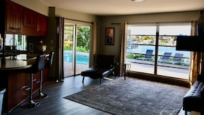 A modern living room with a pool view, a bar area, and a sofa.