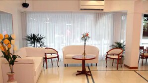 Een moderne woonkamer met een bank, twee fauteuils, een salontafel en een potplant.