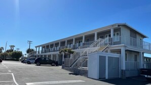 A motel with a two-story structure, a parking lot, and a few cars parked.