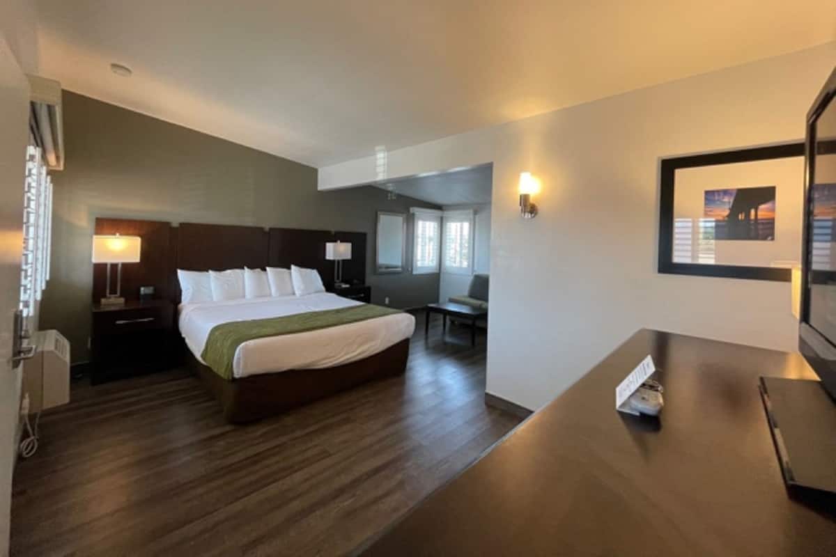 A hotel room with a bed, bedside tables, a desk, and a chair.