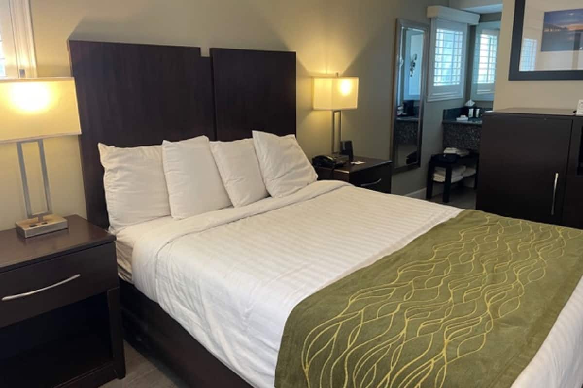 A hotel room with a large bed, two bedside tables, a desk, and a wardrobe.