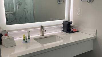 A modern bathroom with a large mirror, two sinks, and a coffee machine.