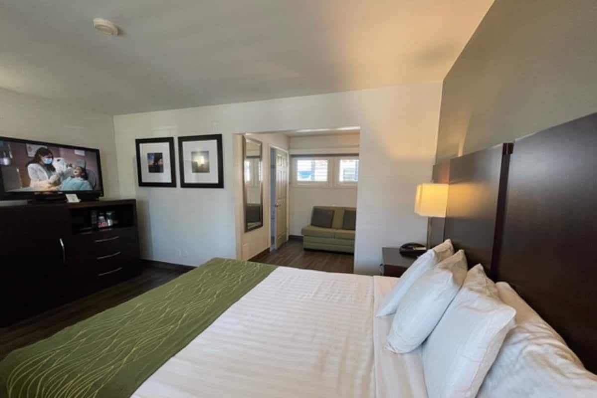 A hotel room with a bed, a TV, a dresser, and a sofa in the background.