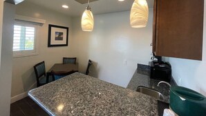 A kitchen with granite countertops, a dining area with a table and chairs, and pendant lighting.
