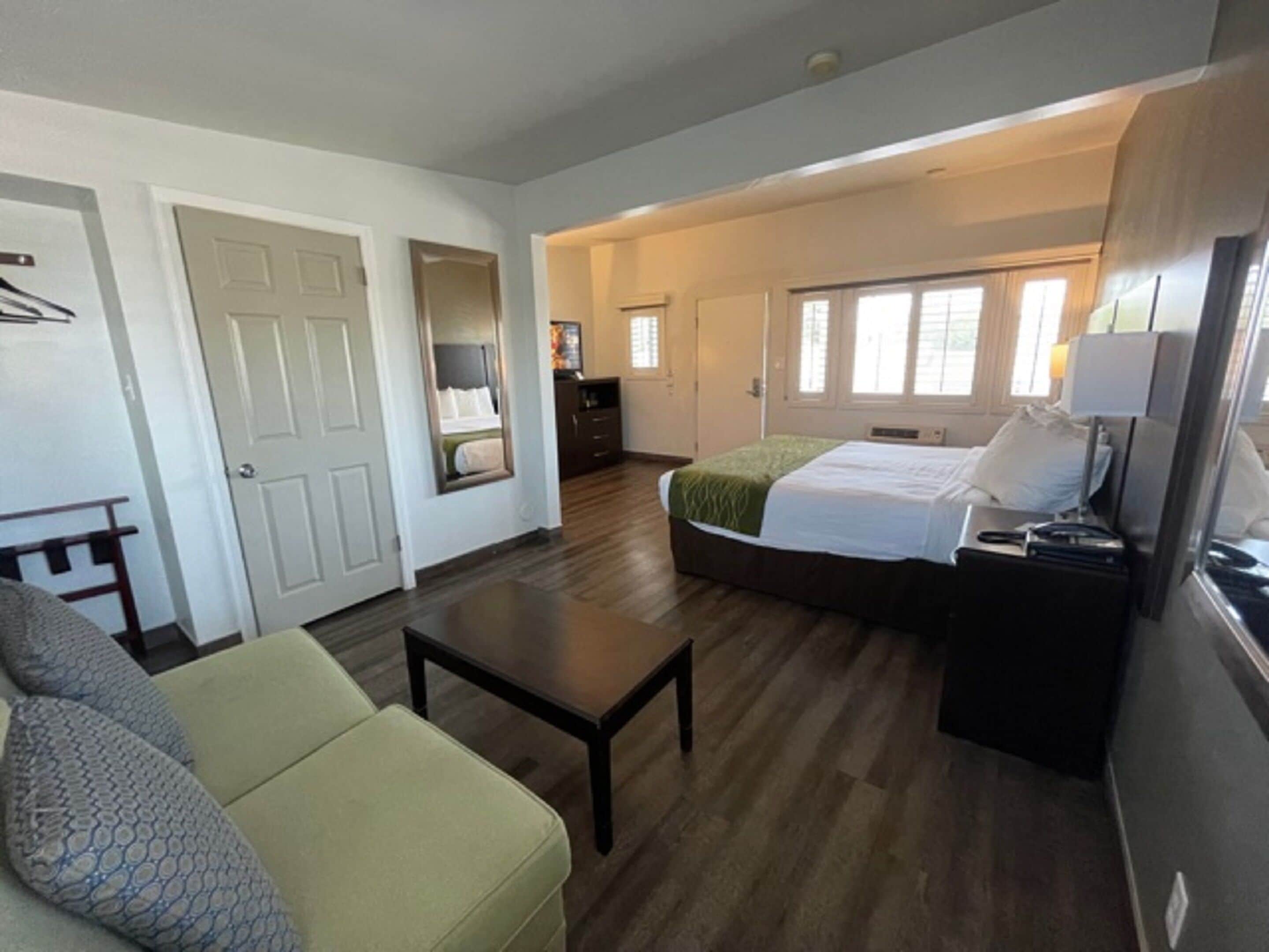 Una habitación de hotel con cama, escritorio, silla y cómoda.