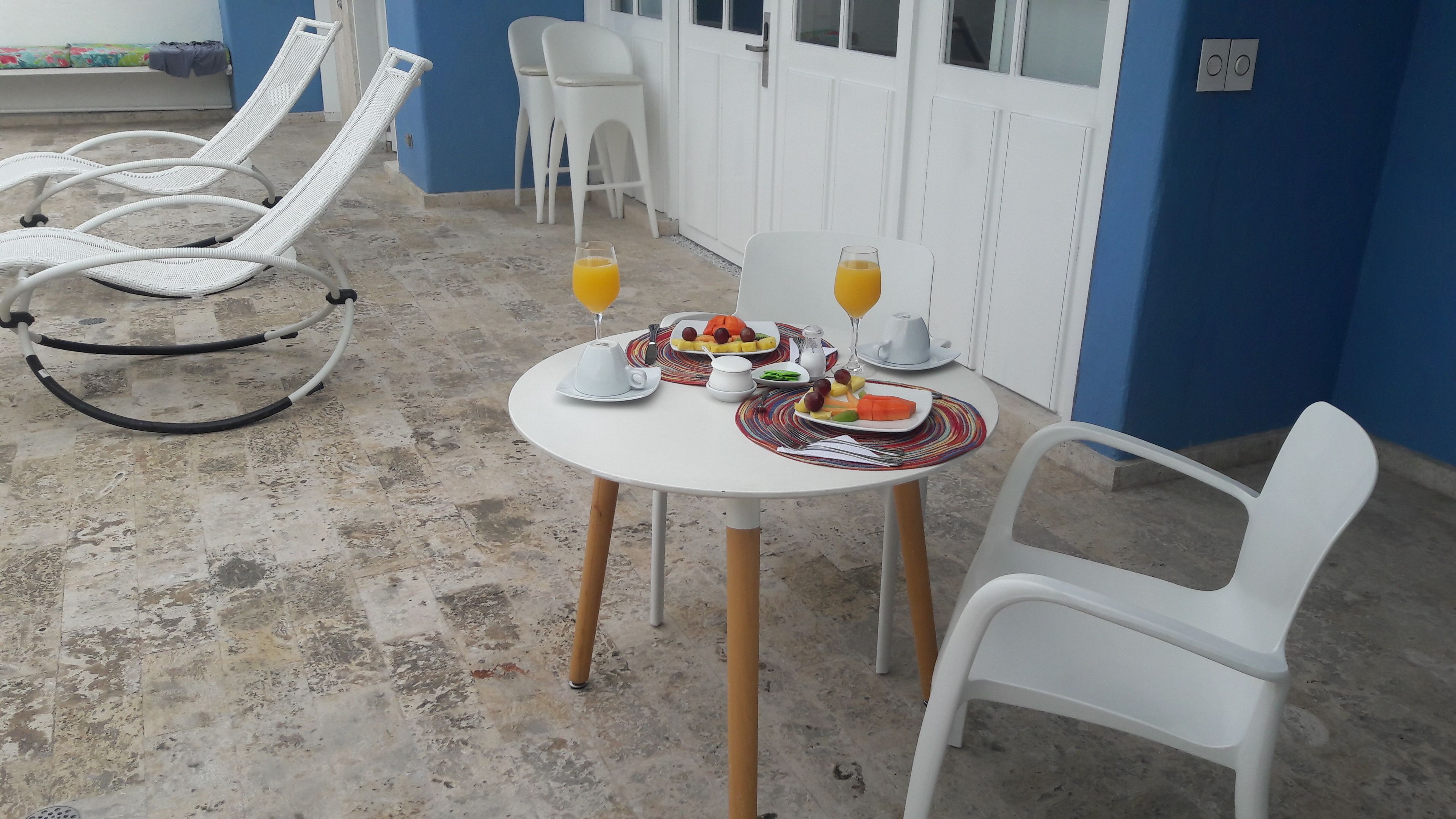 Comedor con una mesa lista para dos personas, con platos de comida y vasos de jugo de naranja.