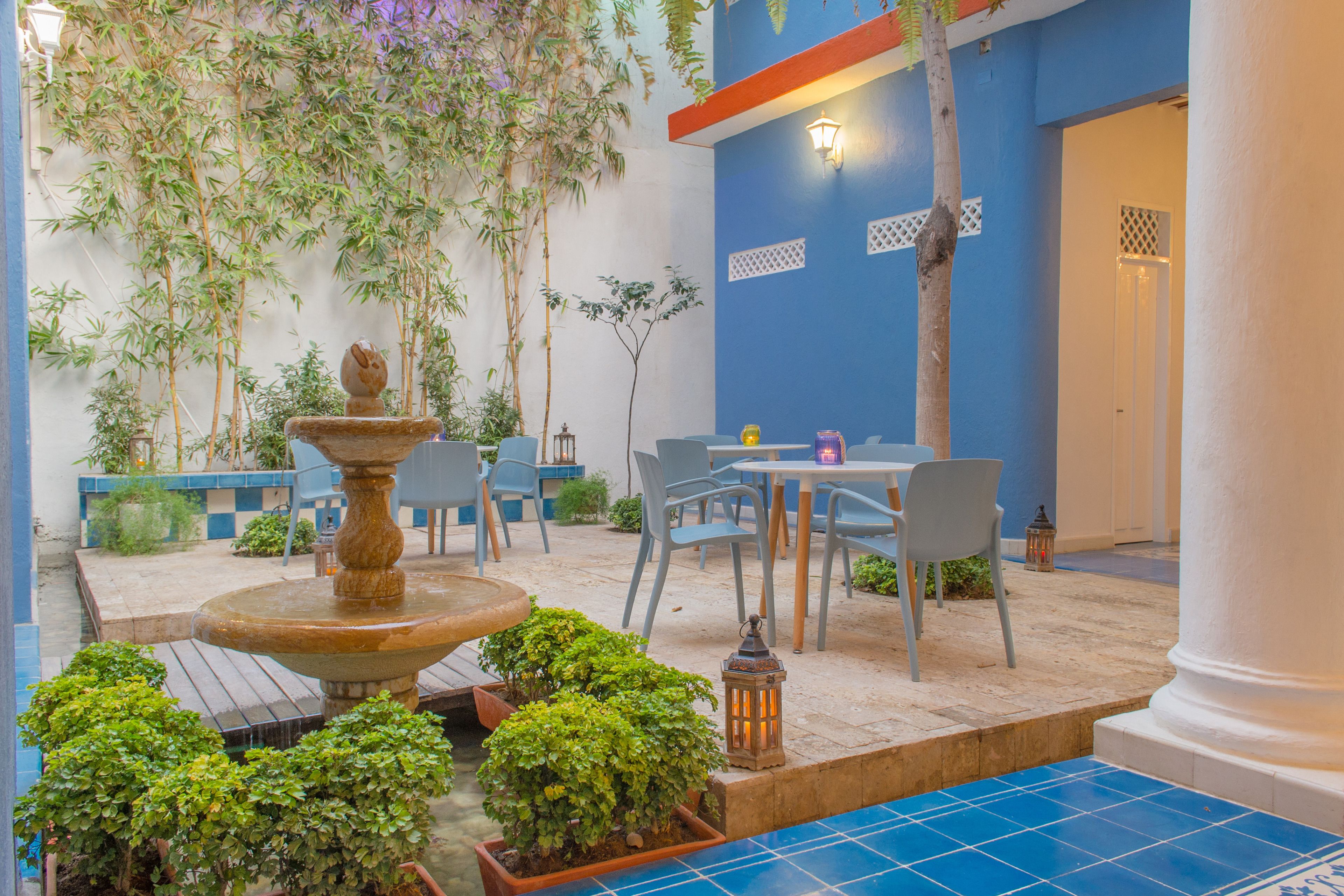 An outdoor patio with a fountain, seating area, and potted plants.