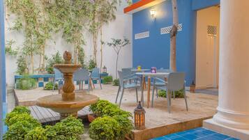 An outdoor patio with a fountain, seating area, and potted plants.