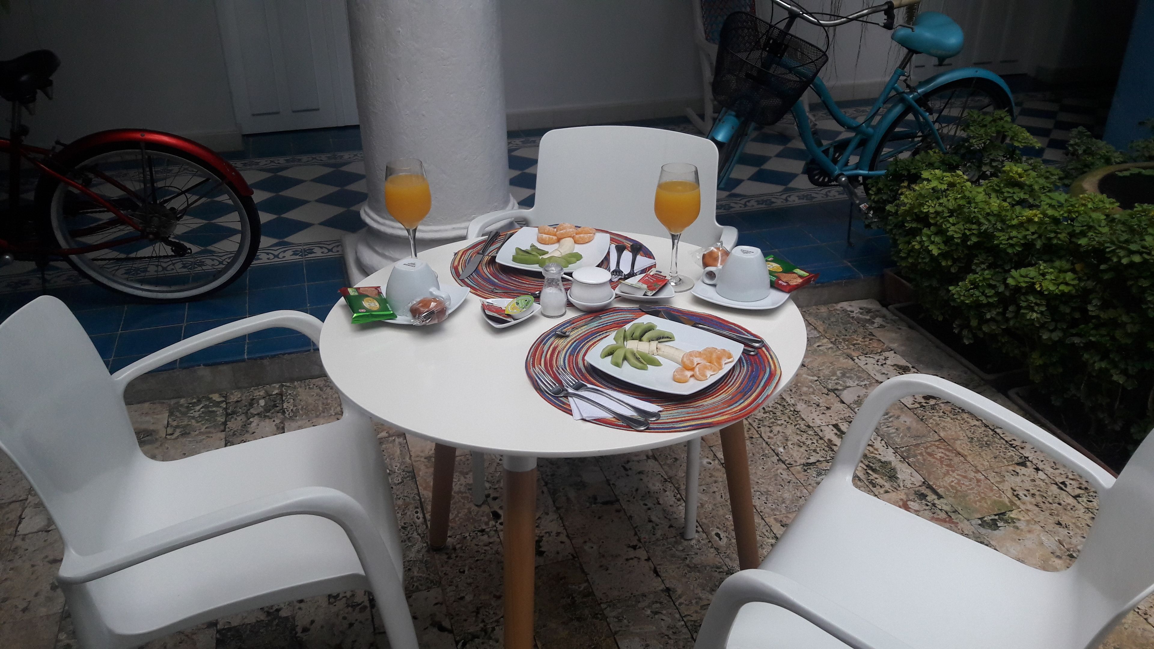 Una mesa servida con platos de comida, vasos de jugo de naranja y una bicicleta al fondo.