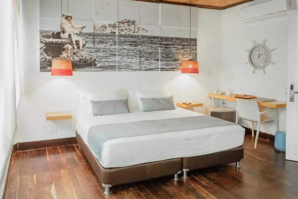 Une chambre à coucher avec un lit, un bureau et une chaise. Il y a une horloge murale et une étagère.