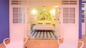 Een kamer met een bed, een kleurrijke muurschildering en een geruit vloerkleed.