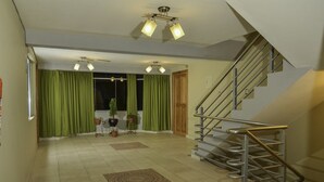 Un interior moderno con una escalera, cortinas verdes e iluminación en el techo.