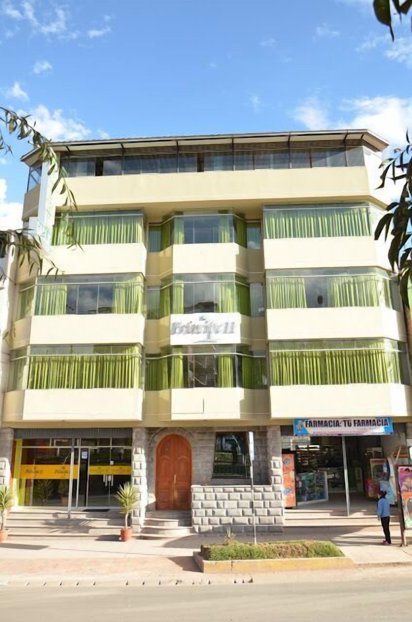 Un edificio de varios pisos con entrada a nivel de calle, un letrero de farmacia visible y una gran puerta de madera.
