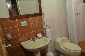 Un baño con lavamanos, inodoro y espejo.