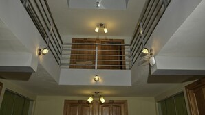 Un interior moderno con una escalera central, armarios de madera e iluminación empotrada.