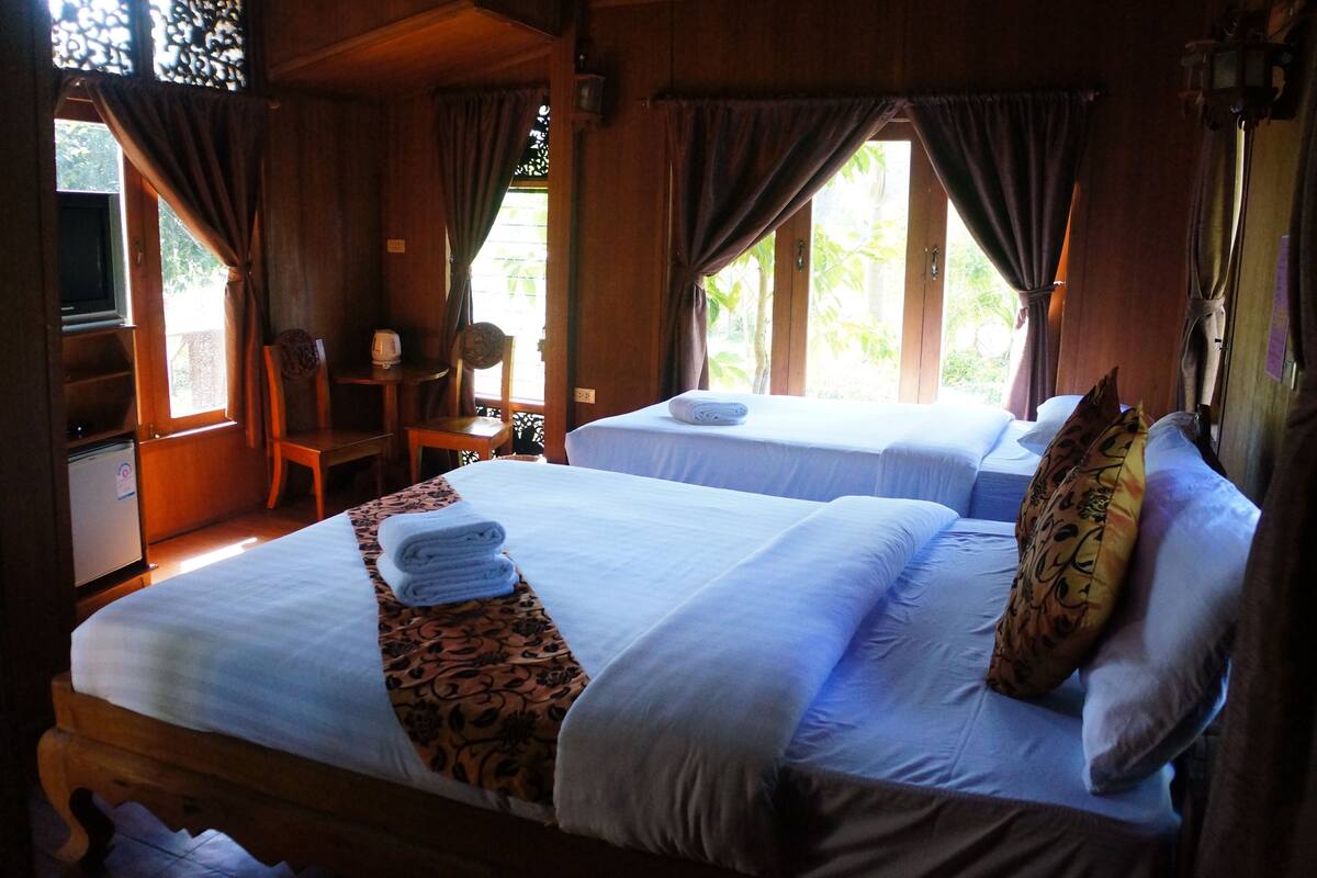 Quarto de cabana de madeira com duas camas, uma mesinha e uma cadeira.