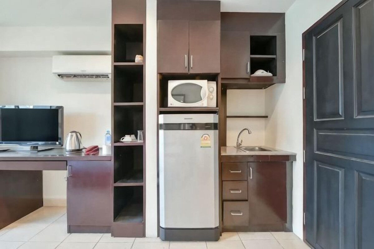 A compact kitchen with a microwave, refrigerator, and a small sink.