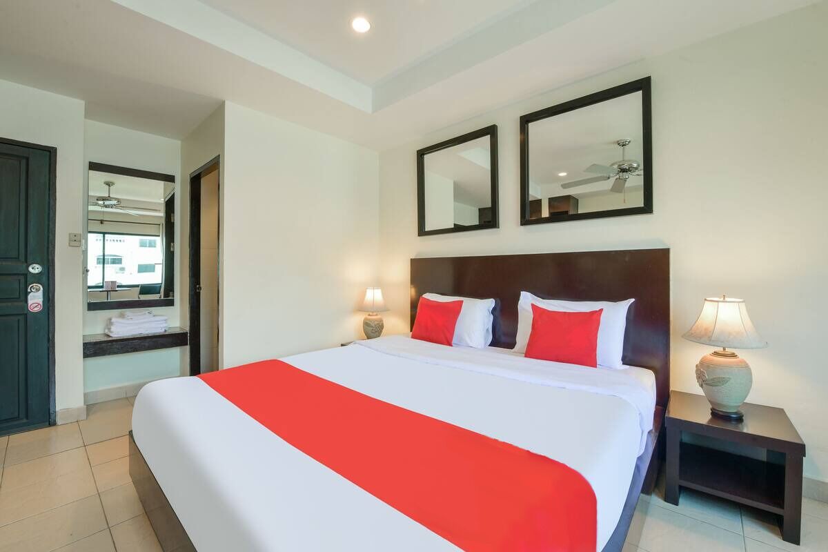 A hotel room with a large bed, two bedside lamps, a wooden headboard, and two wall mirrors.